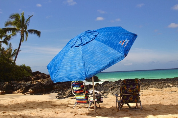 Kihei, Wailea & Makena beach chair rentals and an umbrella on a sunny beach with a clear blue sky.